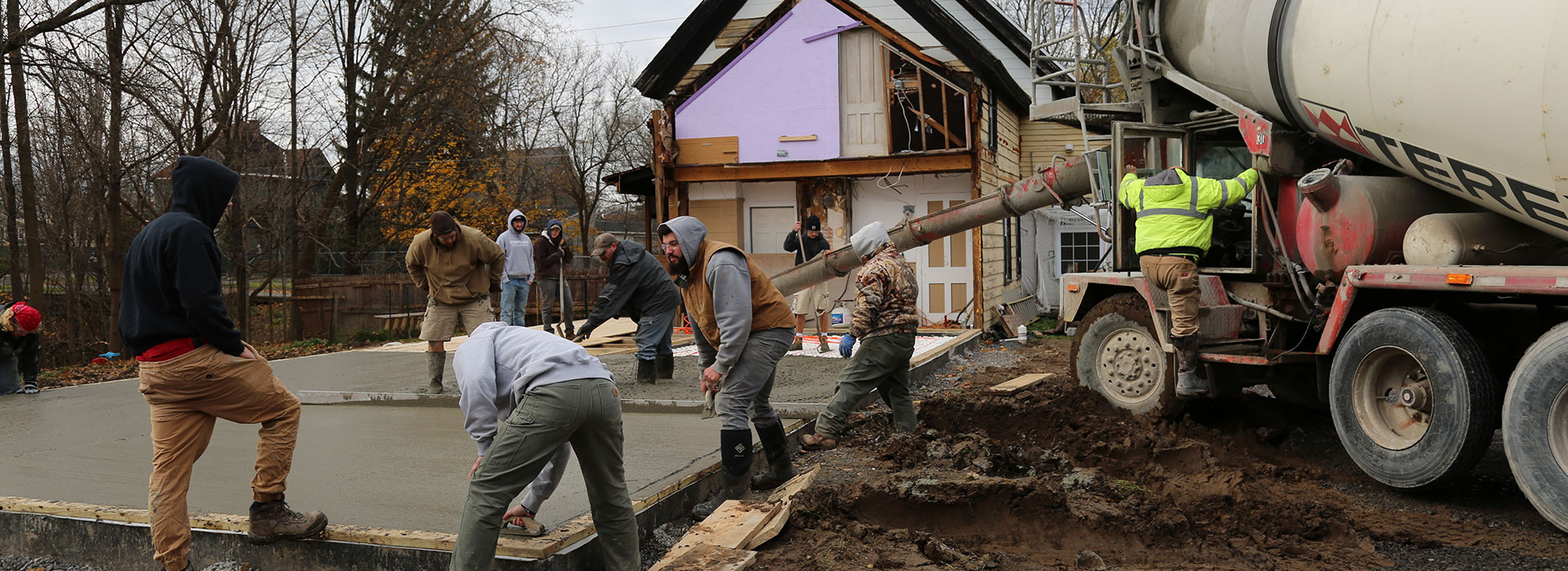 Students in a masonry class pour a concrete slab for a radiant heated floor system.