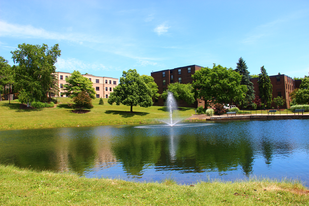 Residence halls overlooking a pond with a fountain.