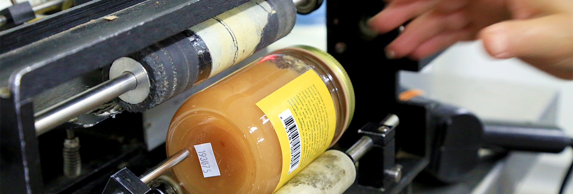 An agriculture business student uses a machine to label their product.